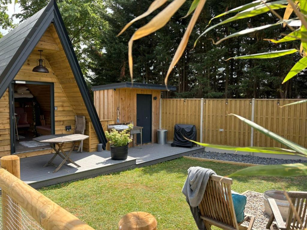 a small cabin with a deck in a backyard at Sycamore Lodge with Hot Tub- Quirky & Romantic in Halstead