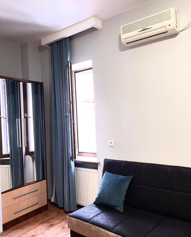 a living room with a black couch and a window at Nana's Mini Hotel in Tbilisi City
