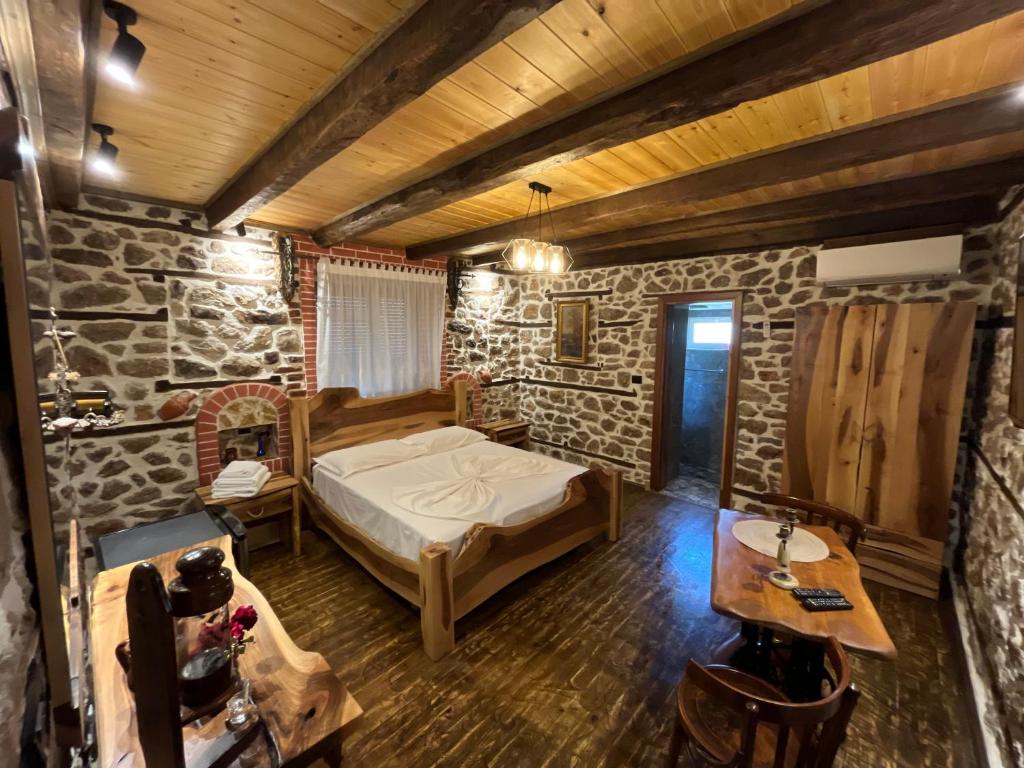 a bedroom with a bed and a stone wall at Vechia Villa Mitllari in Tushemisht