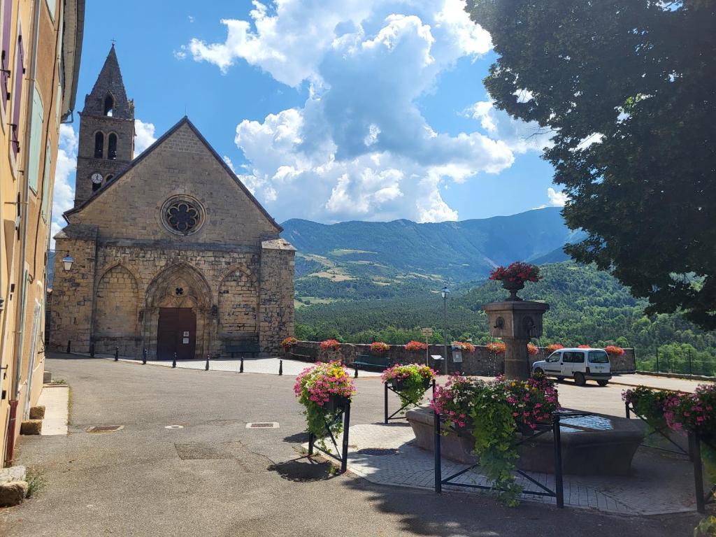 an old church with flowers in front of it at Les Irlandais-Appartement Bayons in Bayons