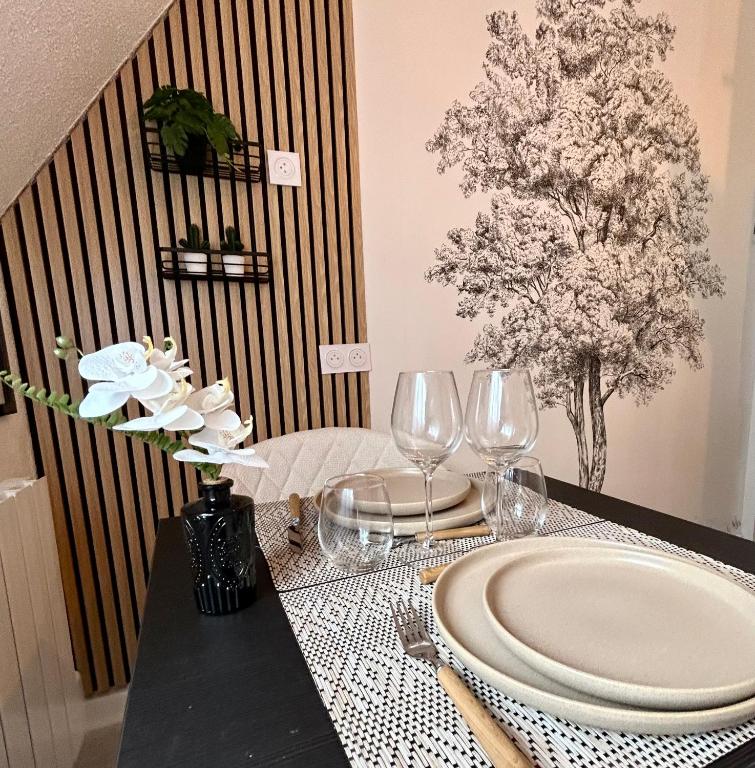 a table with a plate and wine glasses on it at Le Ptit Jumoku in Caen