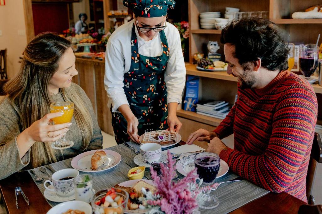 a group of people standing around a table with food at Petit Casa da Montanha in Gramado