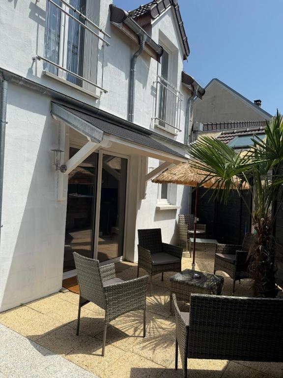 une terrasse avec des chaises, des tables et un parasol dans l'établissement Charmante maison, à Crouy-en-Thelle