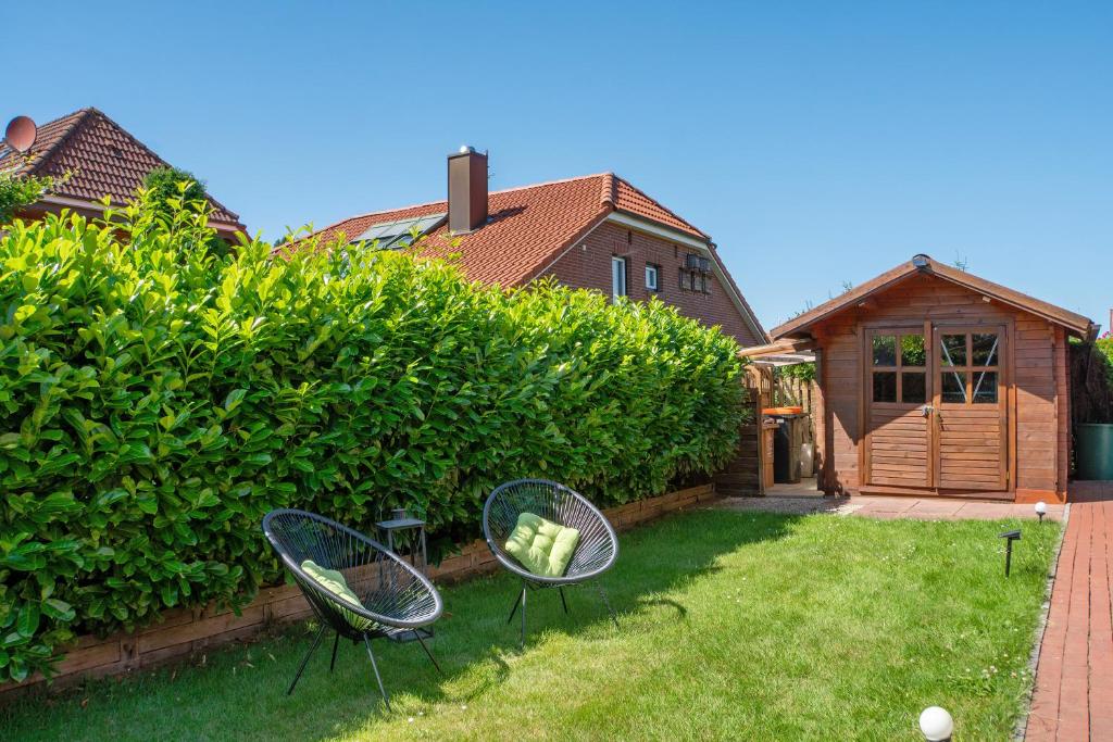 two chairs sitting in the grass in a backyard at Ginas Ferienhaus in Nenndorf