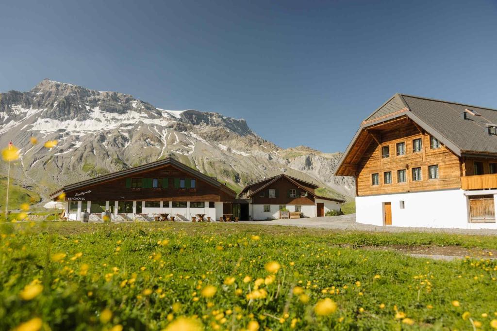 a couple of buildings with a mountain in the background at Berghotel Engstligenalp Adelboden in Adelboden