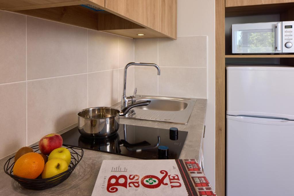une cuisine avec un bol de fruits sur un comptoir dans l'établissement Zenitude Hôtel-Résidences Saint-Paul-lès-Dax, à Saint-Paul-lès-Dax