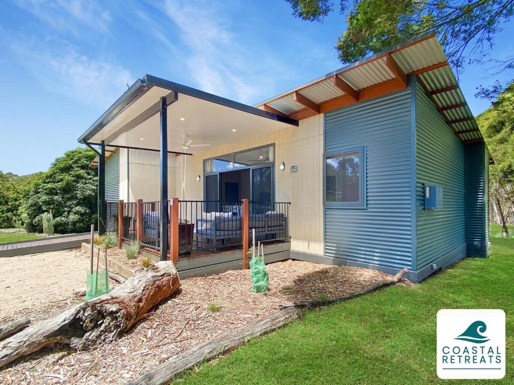 a small house with a large deck in a yard at Superior Poolside Retreat Resort in Cowes