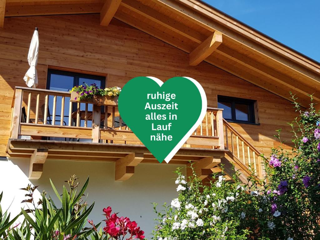 a wooden house with a balcony with a green heart at Ferienhaus Inntal - Ferienwohnung Naunspitz - ruhig schlafen, zentral starten, beliebt bei Wanderern in Kiefersfelden