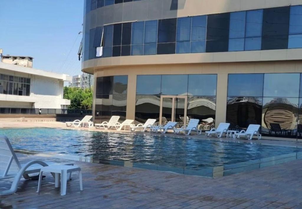 a pool with white lounge chairs in front of a building at Cozy Studio in Esenyurt