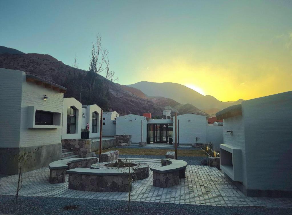 un groupe de bâtiments avec un coucher de soleil en arrière-plan dans l'établissement Los Olivos Purmamarca - Cabañas Boutique, à Purmamarca