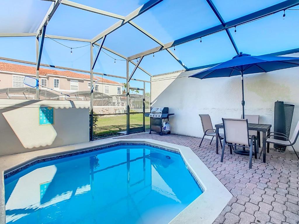 einen Pool mit einem Tisch und einem Sonnenschirm in der Unterkunft Lovely 3BR Villa - Bella Vida Resort - Pool & BBQ! in Kissimmee