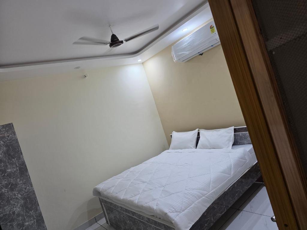 a small bed in a room with a ceiling fan at Green Homestay in Bahādrābād