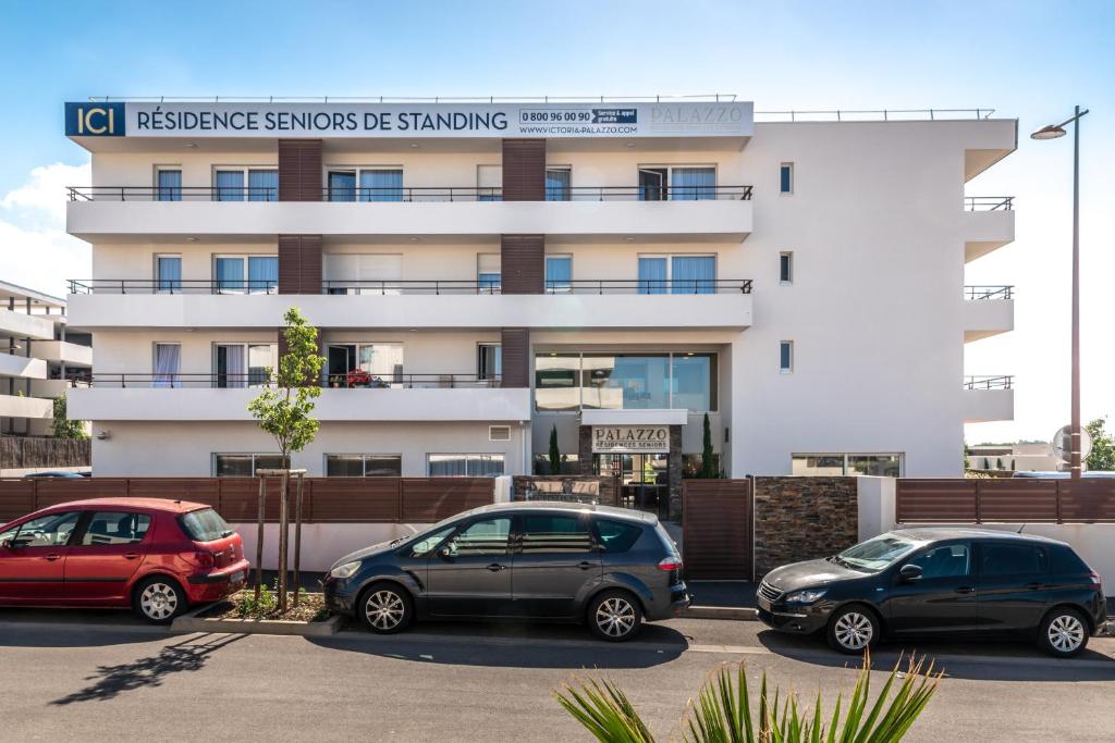 three cars parked in a parking lot in front of a building at Zenitude Hôtel-Résidences Perpignan in Perpignan