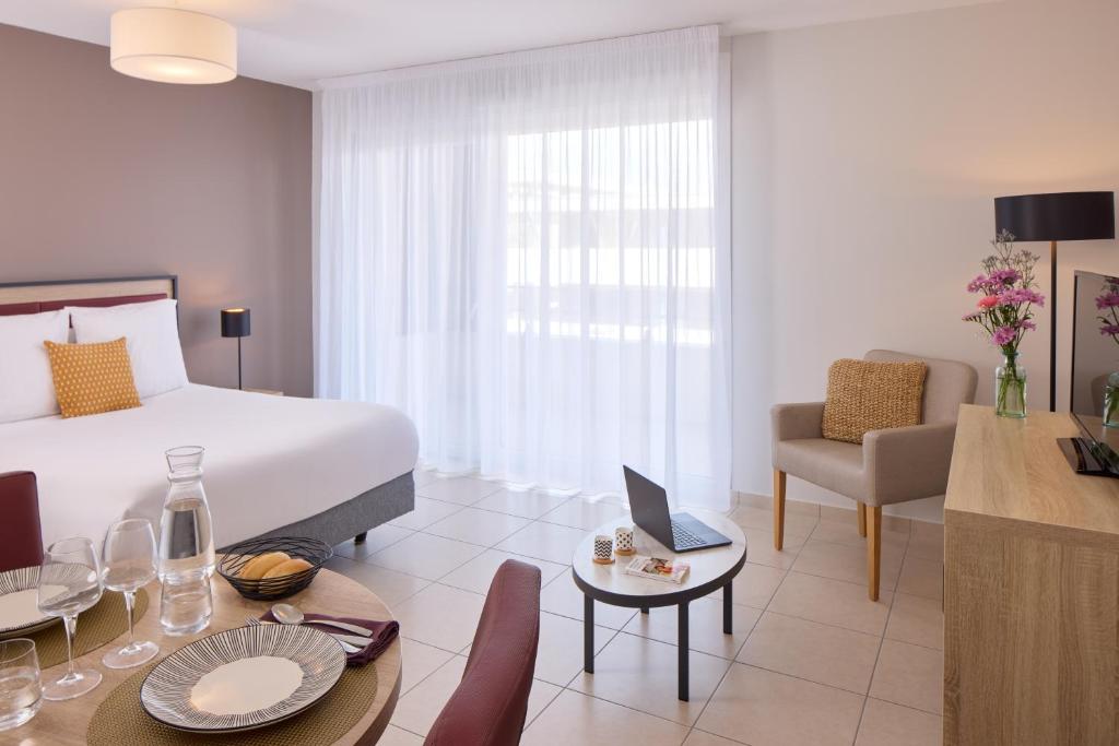 a hotel room with a bed and a table and chairs at Zenitude Hôtel-Résidences Perpignan in Perpignan