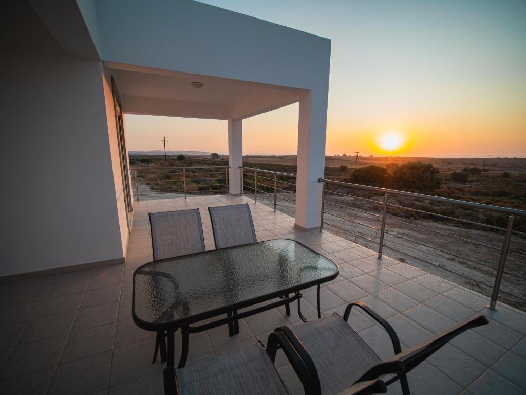 una mesa y sillas en un balcón con vistas a la puesta de sol en Casa Flora, en Kefalos