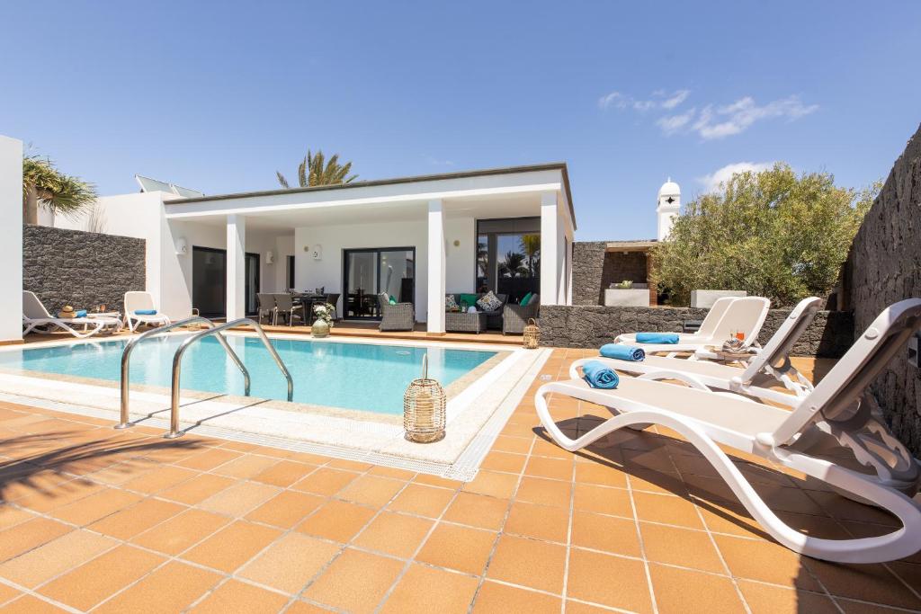a villa with a swimming pool and two lounge chairs at Villas Mamma Mia pool heat Private & Jacuzzi in Playa Blanca