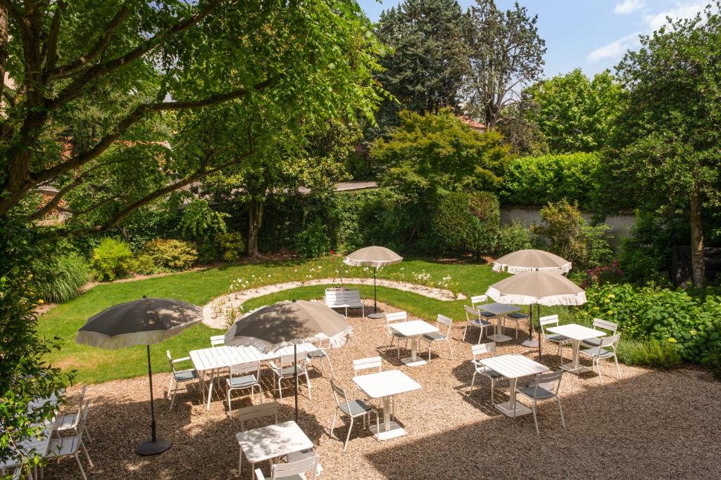 un groupe de tables et de chaises avec parasols dans l'établissement Hôtel Maison Lacassagne Lyon, à Lyon