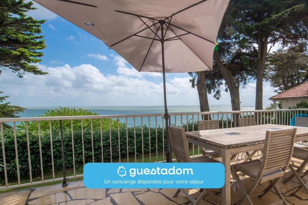 une table et des chaises sur un balcon avec un parasol dans l'établissement La Vue Mer - 50m de la plage - Parking, à Pornic