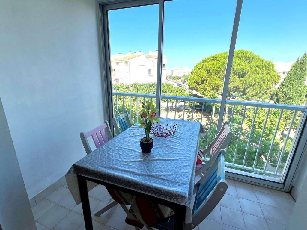 une table avec un vase de fleurs sur un balcon dans l'établissement Charmant 2 pièces cabine moderne, parking inclus, proche plage et commerces, animaux admis - FR-1-307-8, au Grau-du-Roi