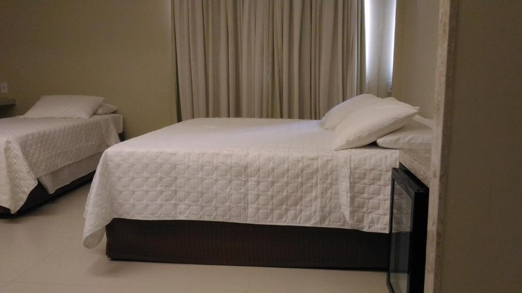 a bedroom with two beds with white sheets and a window at Uchôa Teresina Hotel in Teresina