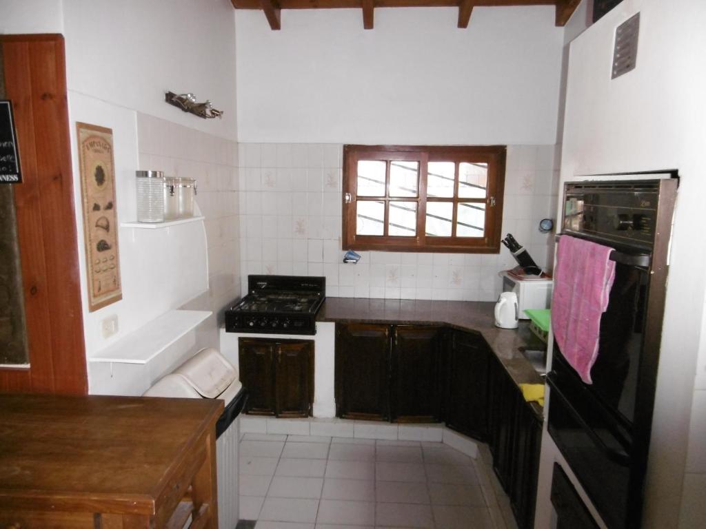 a kitchen with a sink, stove and a window at Hostel La Casa de Tounens in Puerto Madryn