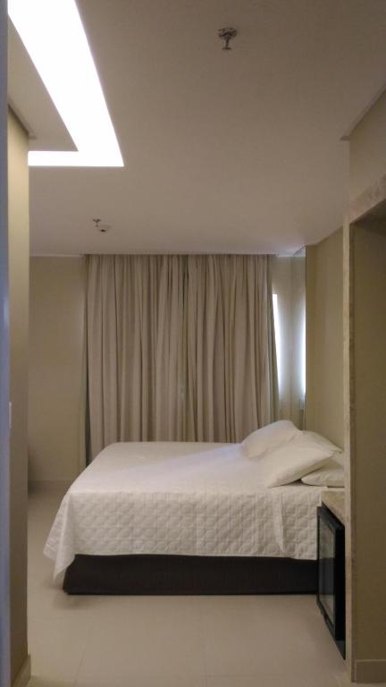 a bedroom with a white bed with a window at Uchôa Teresina Hotel in Teresina
