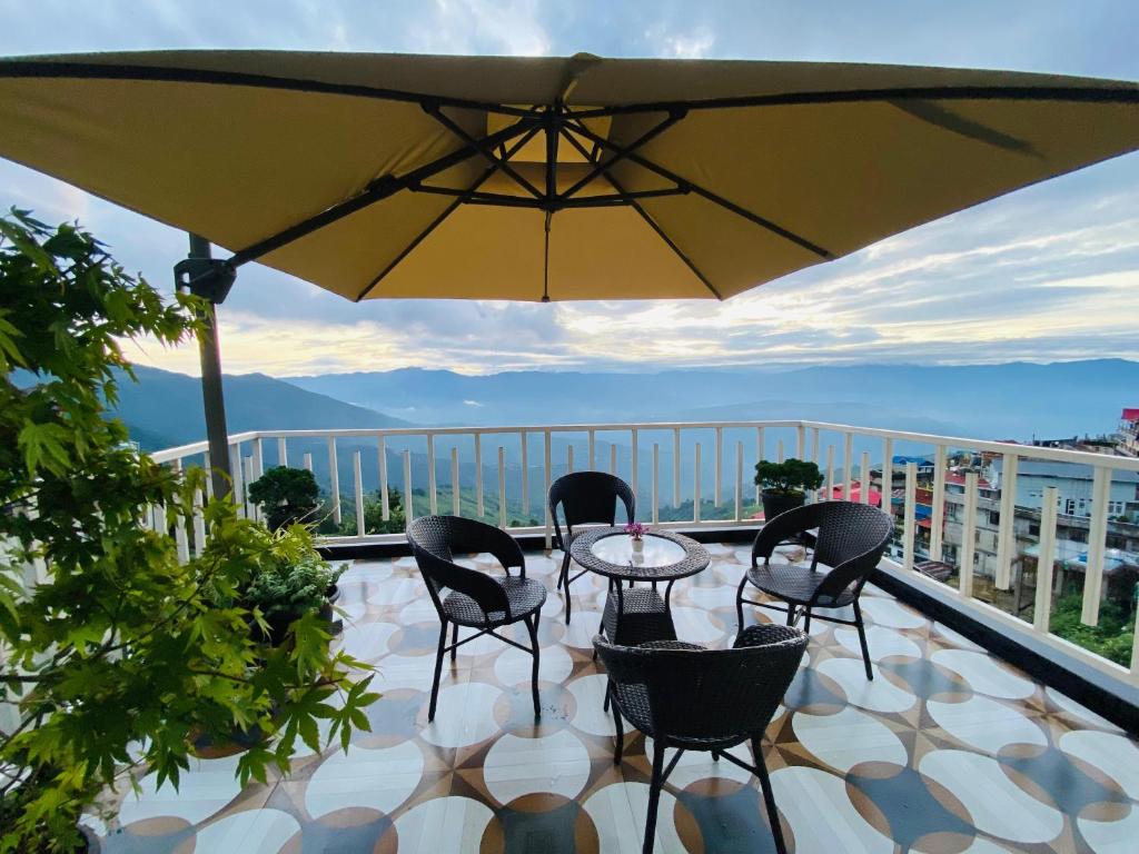Un patio con una mesa y sillas y una sombrilla. en Denka's, en Darjeeling