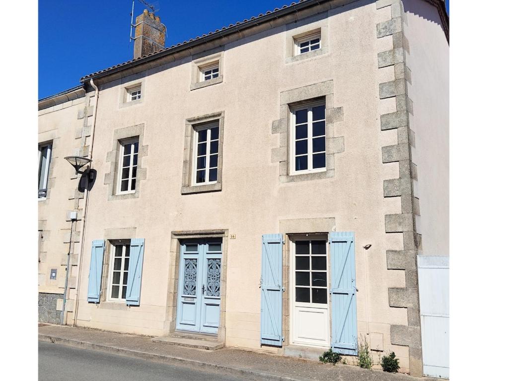 a large brick building with blue doors and a clock tower at Gîte de l'Église de la Pommeraie in La Pommeraie-sur-Sèvre