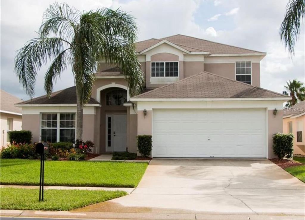 una casa con un garaje y una palmera en Amazing Retreat at Lake Berkley, en Kissimmee