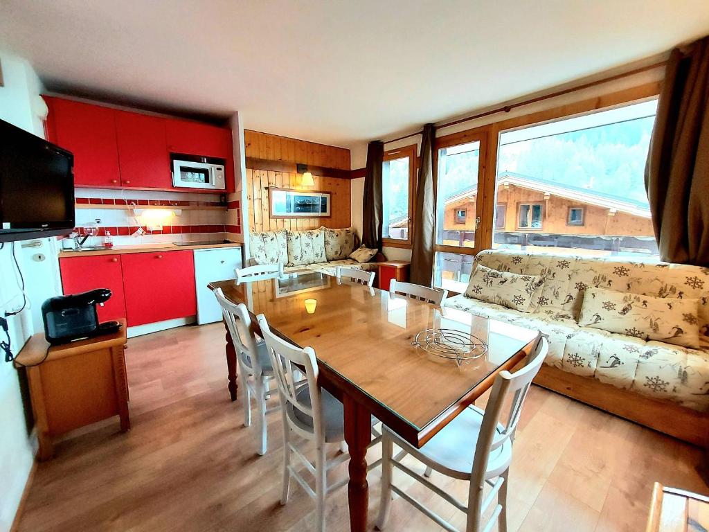Il comprend un salon avec une table en bois et une cuisine. dans l'établissement Charmant 2P rénové avec balcon, proche commerces, casier à ski et parking, Plagne 1800 - FR-1-351-160, à La Plagne Tarentaise