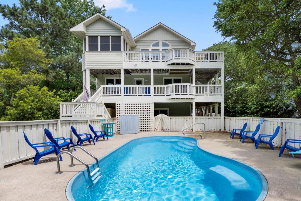a house with a swimming pool and blue chairs at Ocean Escape in Corolla