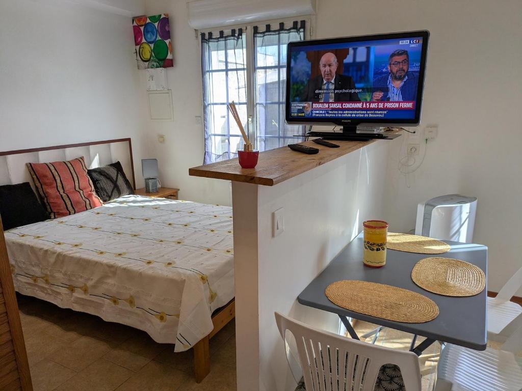 une chambre avec un lit et une télévision à écran plat dans l'établissement Maison loft et jardin privatif 400m plage Royan Pontaillac, à Vaux-sur-Mer