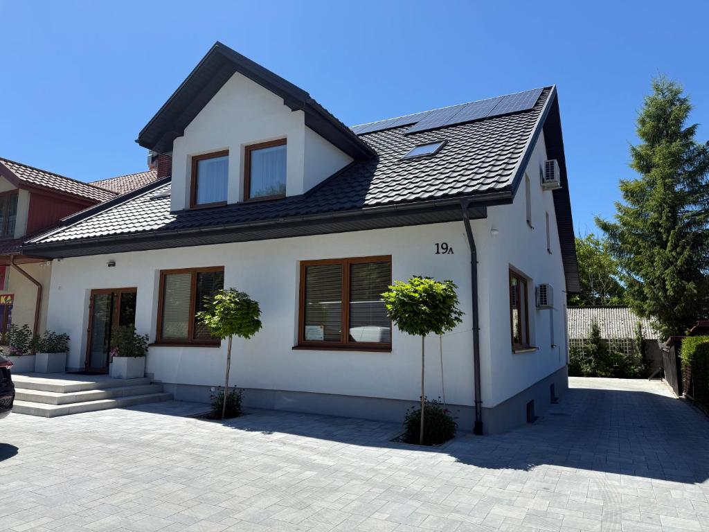 a white house with a black roof at Apartamenty Zamojska in Zwierzyniec