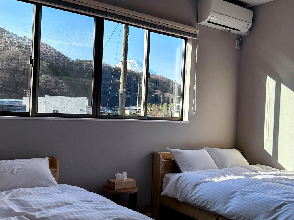富士河口湖町にあるwag ur day - Spacious Villa Sleeps 10 Pet-Friendly dogs and cats Up to 7 Huge Private Dog Runの大きな窓のある部屋にベッドが2つある