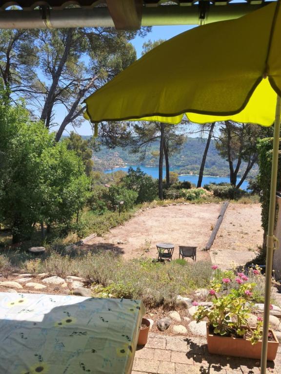 a yellow umbrella and a bench in a yard at Panoramic lake view in Esparron-de-Verdon