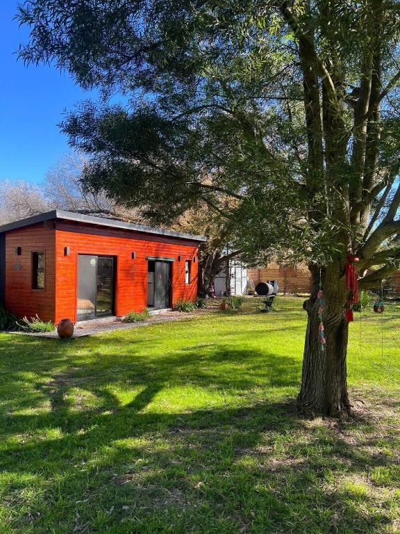 an orange house in a field with a tree at Confortable cabaña con parrilla in Chascomús