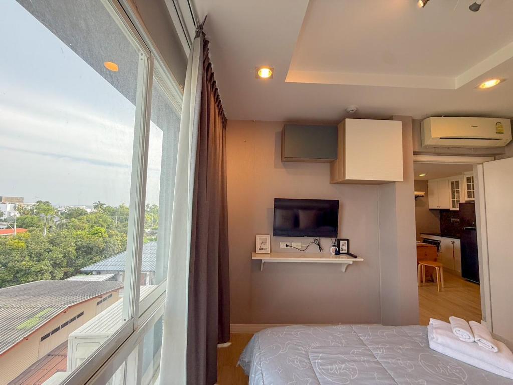 una habitación con una cama y una ventana grande en Finn Room Plus 38 sqm & The Patio by BHB, en Bangsaen Sai 1