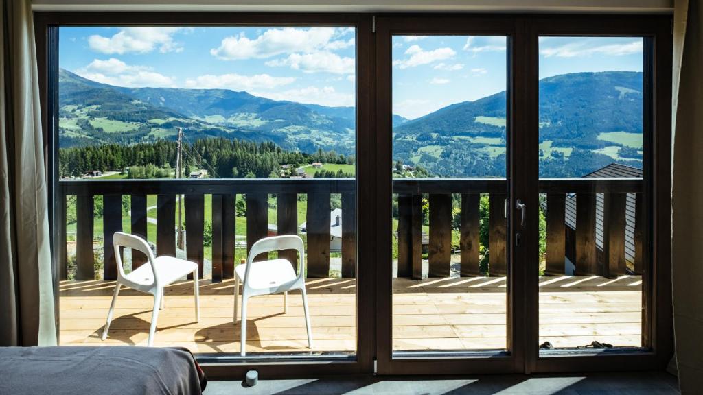 una stanza con un balcone con due sedie bianche su una terrazza di Art-Lodge TinyHouses ad Afritz