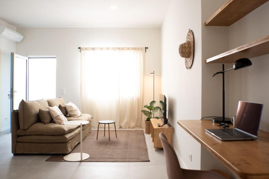 a living room with a couch and a desk with a laptop at Outsite Sagres - Work, Connect, Explore in Sagres