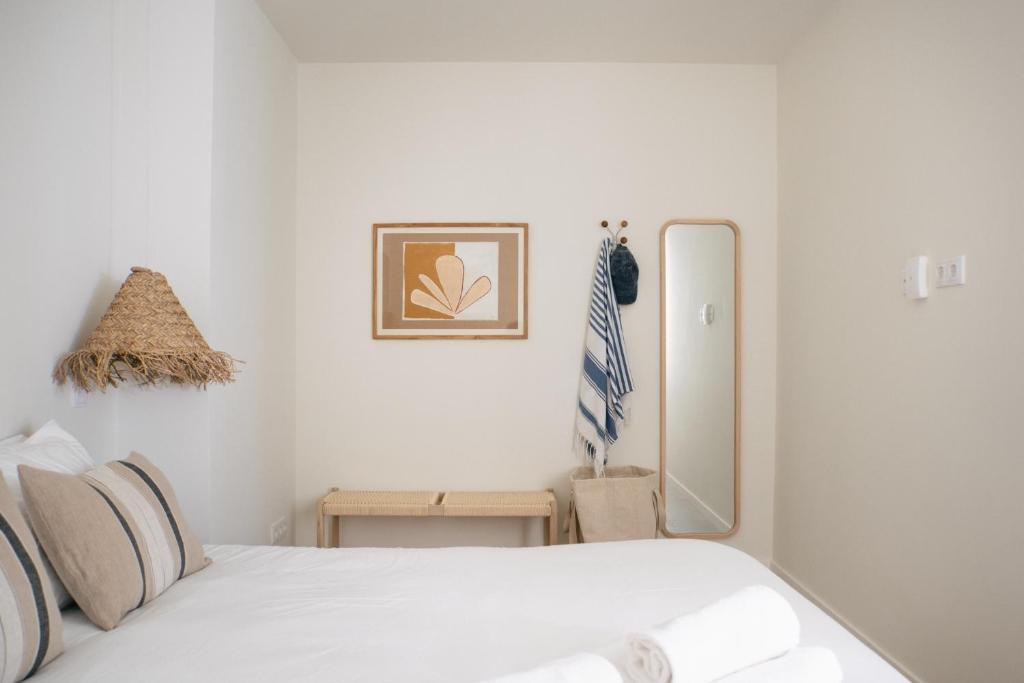 a white bedroom with a bed and a mirror at Outsite Sagres in Sagres