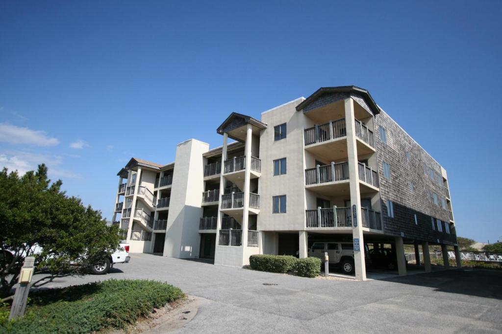 Un edificio de apartamentos con un estacionamiento enfrente. en Heron Cove 302N, en Nags Head