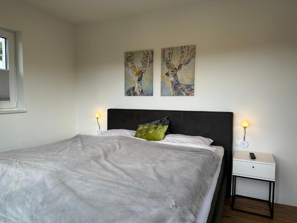 a bedroom with a bed with two pictures on the wall at Ferienhaus Diemelblick 14 mit Seeblick und Sauna am Diemelsee für bis zu 6 Gäste in Diemelsee