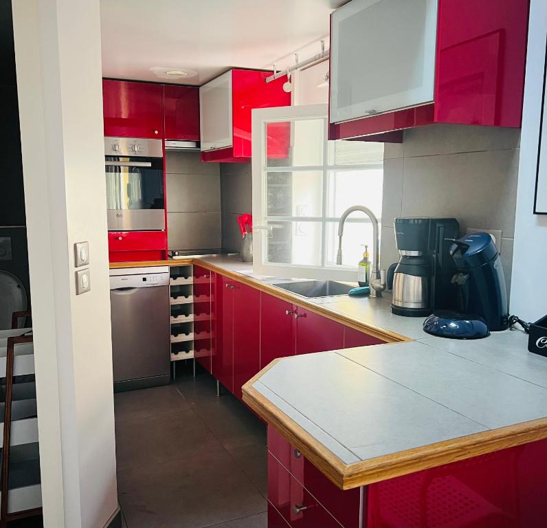 a kitchen with red cabinets and a sink at Petite maison indépendante à 20min de Paris in Bonneuil-sur-Marne