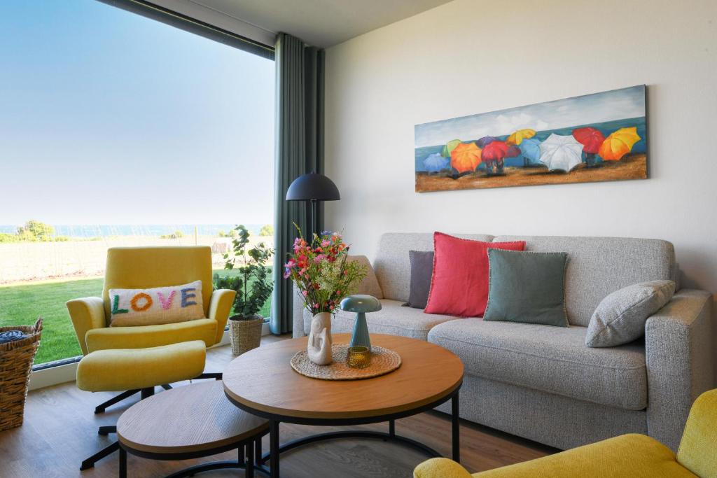 a living room with a couch and chairs and a table at Lykke – Traumhafte Ferienwohnung mit Garten und Meerblick in erster Reihe! in Fehmarn