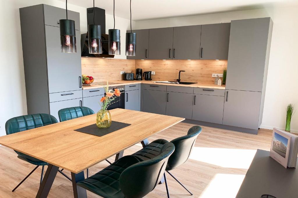 a kitchen with a wooden table and blue chairs at KÜSTE33/23 – Seestern - Exklusive Ferienwohnung mit Sauna & nah am Strand! in Butjadingen OT Tossens