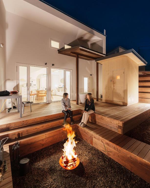 two people sitting around a fire in a house at 軽井沢一棟貸しBBQサウナつき別荘- YURAGI - TSUKI me CHILL in Miyota