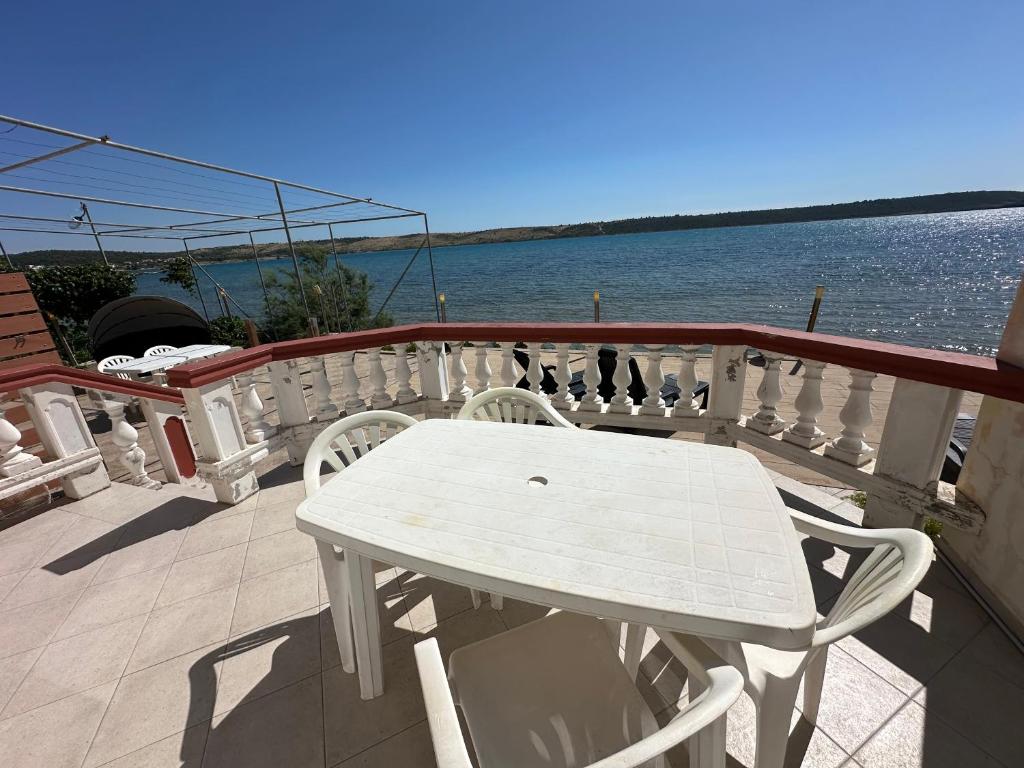 a white table and chairs on a balcony overlooking the water at Villa M ground floor Apartment for 4 persons in Ljubač