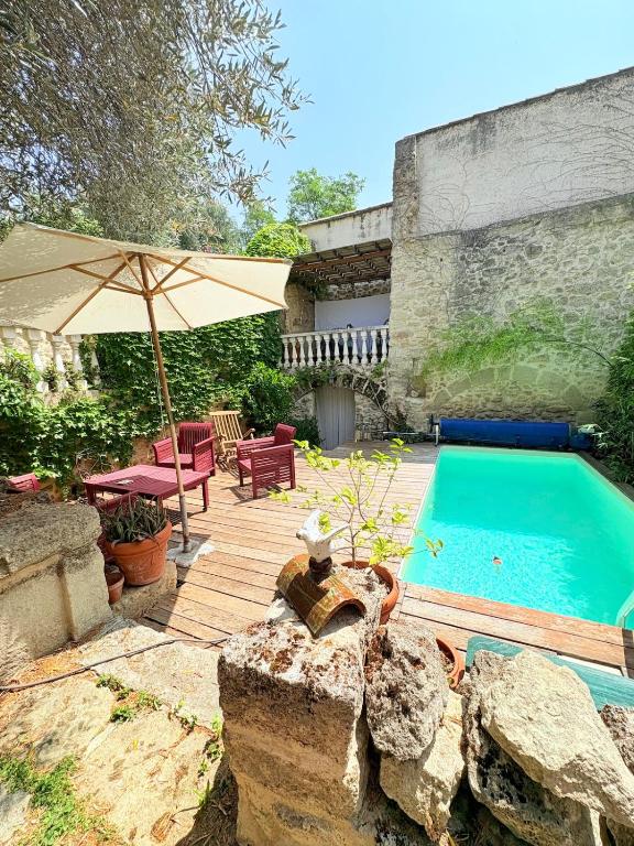 einen Hinterhof mit Pool und Sonnenschirm in der Unterkunft Les jardins de Montbazin in Montbazin