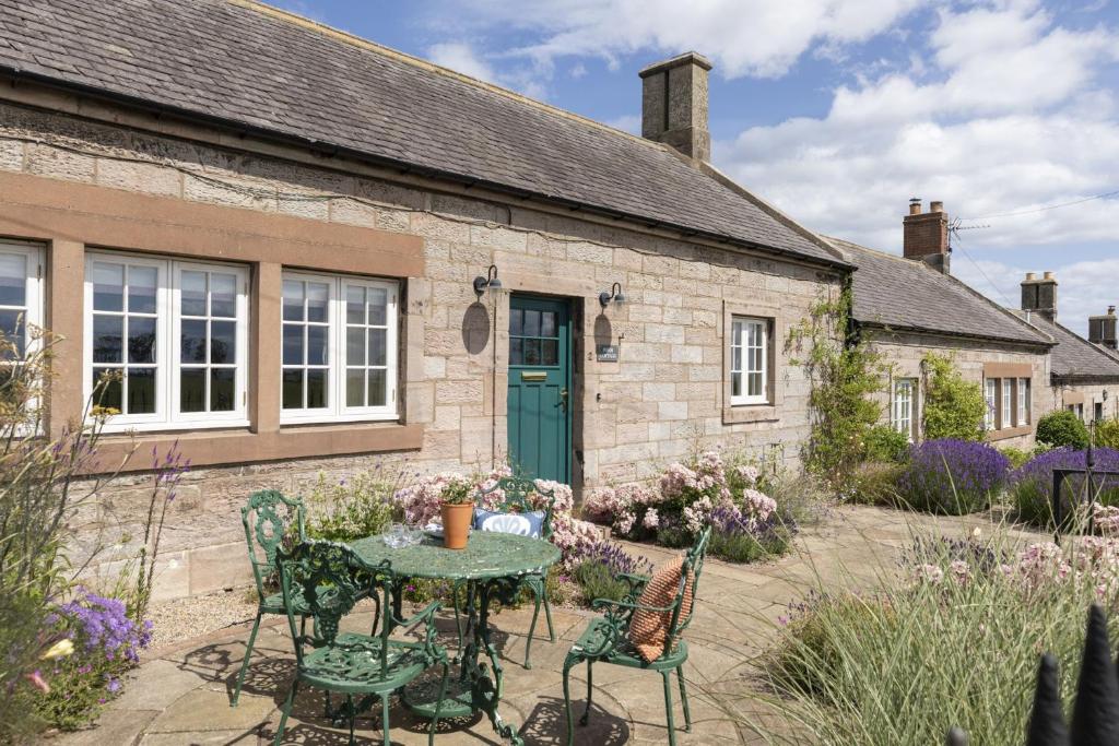 a stone cottage with a table and chairs in front of it at Farm Cottage in Berwick-Upon-Tweed