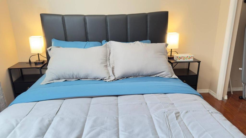 a large bed with blue sheets and white pillows at The Panatella Pad /Guest’s Private Suite in Calgary